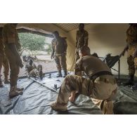 Un instructeur du Service de santé des armées (SSA) encadre l'installation d'un brancard à l'intérieur d'un module sanitaire par des stagiaires burkinabè à Dori, au Burkina Faso.