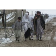 Consultations pour la population civile à l'hôpital jordanien de l'aéroport de Mazar e Charif. Portrait d'une famille afghane, dont la femme est voilée, sortant de l'hôpital.