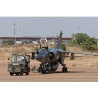 Tractage d'un avion Mirage F1CR par un tracteur Tracma à son arrivée sur le tarmac de l'aéroport de Bamako, au Mali.