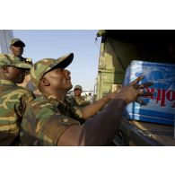 Des soldats togolais chargent des cartons de bouteilles d'eau à l'arrière d'un camion sur l'aéroport de Bamako, au Mali.