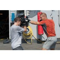 Des marins s'exercent à la boxe sur le pont arrière de la frégate de surveillance Ventôse, en mer des Caraïbes.