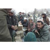 Marchands pratiquant le change au marché de l'argent du centre-ville de Mazar e Charif, veillant sur des paquets de liasses de billets en afghani, la monnaie locale. Transaction avec un client.