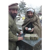 Marchands pratiquant le change au marché de l'argent du centre-ville de Mazar e Charif, veillant sur des paquets de liasses de billets en afghani, la monnaie locale. Transaction avec un client.