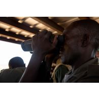 Un soldat malien observe le terrain au moyen de jumelles VECTOR 21 lors d'une formation au guidage aérien tactique avancé (GATA) à Gao, au Mali.