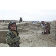 Camp de réfugiés afghans à Mazar e Charif. Portrait d'une enfant dans les bras d'une femme. Un petit garçon au premier plan.