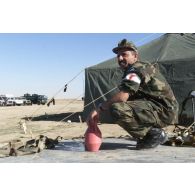 Un soldat jordanien, portant un brassard du Croissant-Rouge, symbole des services de santé, se lave les mains au pied d'une tente.