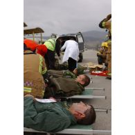 Triage des blessés selon les priorités d'urgence et premiers soins par les pompiers de l'aéroport et les médecins locaux avant évacuation.