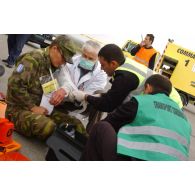 Triage des blessés selon les priorités d'urgence et premiers soins par les pompiers de l'aéroport et les médecins locaux avant évacuation.