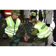 Soins aux blessés dans la zone de triage avec ordre de priorité d'urgence, sous l'oeil des observateurs du service de santé.