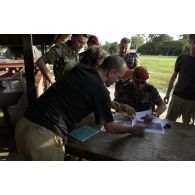 Conférence de presse du général Henri Poncet, COMFOR Licorne (commandant de la force), qui montre au groupe un article de presse illustré de photos, en présence du colonel Aussavy, CONSCOM (conseiller communication).