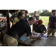 Conférence de presse du général Henri Poncet, COMFOR Licorne (commandant de la force), qui montre au groupe un article de presse illustré de photos, en présence du colonel Aussavy, CONSCOM (conseiller communication).