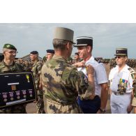 Le général de brigade Pierre Gillet, commandant la force Sangaris, remet la médaille militaire à un gendarme du peloton de gendarmerie mobile, lors du rassemblement des troupes composant le PCIAT (poste de commandement interarmées de théâtre) dans le cadre de la commémoration du 8 mai 1945.