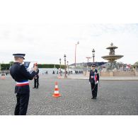 Un officier de l'école nationale supérieure de la Police nationale (ENSPN) prend en photographie sa camarade avec son téléphone avant le défilé à pied du 14 juillet sur la place de la Concorde.