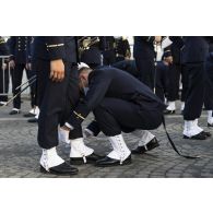 Derniers préparatifs pour les élèves de l'école navale qui ajustent leurs guêtres avant la cérémonie du 14 juillet sur la place de la Concorde.