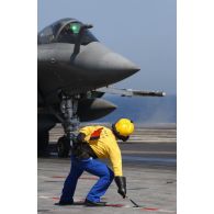 Sur le porte-avions Charles de Gaulle, un équipier de pont d’envol (chien jaune) donne le vert pour le catapultage d’un Rafale.