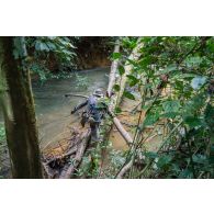 Un soldat du 7e bataillon de chasseurs alpins (BCA) franchit un marécage sur des troncs d'arbre à Maripasoula, en Guyane française.