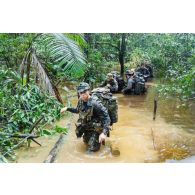 Des soldats du 7e bataillon de chasseurs alpins (BCA) franchissent un marécage au moyen d'une corde à Maripasoula, en Guyane française.