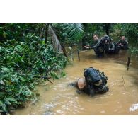 Des soldats du 7e bataillon de chasseurs alpins (BCA) franchissent un marécage au moyen d'une corde à Maripasoula, en Guyane française.