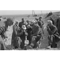 Un groupe d'officiers entoure un téléphone de campagne, à gauche, au second plan, le colonel (Oberst) Fritz Bayerlein.