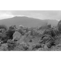 Un groupe de soldats est allongé au sommet d'une colline, tir d'une mitrailleuse MG-34.