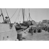 Activités dans le port de Tobrouk, déchargement d'essence (jerrycans et futs) par des prisonniers alliés.