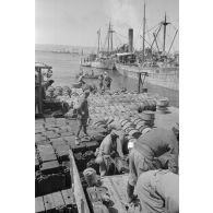 Activités dans le port de Tobrouk, déchargement d'essence (jerrycans et futs) par des prisonniers alliés.