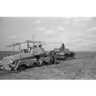 Un véhicule de reconnaissance Sd.Kfz 263 (8 RAD) s'est embourbé, un char Panzer III le tracte.