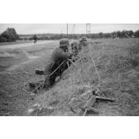 Des fantassins allemands en position défensive, au premier plan un mitrailleur équipé d'une MG-34.