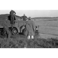 Dépannage d'un véhicule britannique par un semi-chenillé Sd.kfz.7, on note l'inscription Gruppe Hägele sur le blindé allemand.