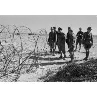 Le général (Generalleutnant) Erwin Rommel inspecte un réseau de fils barbelés en compagnie d'officiers allemands et italiens.