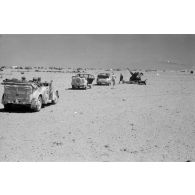 Des voitures Kfz-15, Kfz-21 et Kfz-3 qui composent l'état-major de Rommel près d'un camp et de canons italiens.