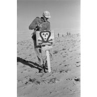 Un soldat installe le panneau prévenant de la présence d'un champ de mines.