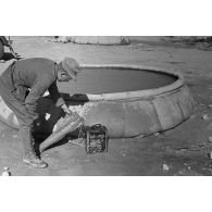 Un soldat remplit une nourrice d'eau. Cette eau a été recueillie dans un bac souple circulaire.