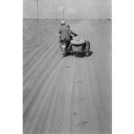 Un side-car BMW R75 roule dans le désert, le long de la piste baptisée du télégraphe.