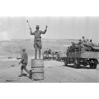 La marche d'une colonne de véhicules est régulée par un Hauptfeldwebel de la Feldgendarmerie.