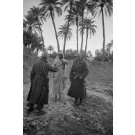 Un officier et un caporal (Gefreiter), tous deux armés de MP-40, parlent avec un paysan libyen.