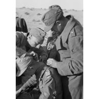 Un Oberleutnant, aidé par un Oberfeldwebel, soigne plusieurs blessés légers.