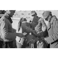 Un Oberleutnant, aidé par un Oberfeldwebel, soigne plusieurs blessés légers.