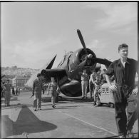 Un avion de chasse Corsair, sur le pont d'envol du porte-avions Arromanches au mouillage dans la rade d'Alger.