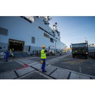 Des marins guident le chargement d'un camion TRM-10000 à bord du bâtiment de projection et de commandement (BPC) Le Tonnerre à Toulon.