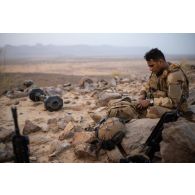 Un soldat récupère ses effets dans sa musette au sommet d'un piton rocheux dans la région de Mopti, au Mali.