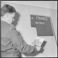 Algérie. 5e bureau. Un stagiaire officier regarde une photo pour la création d'une affiche de propagande.