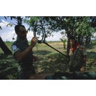 Apprentissage du déminage à l'aide d'un détecteur de mines dit poêle à frire par un élève cambodgien encadré par un casque bleu.