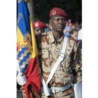 Portrait d'un soldat de la garde nationale et nomade du Tchad (GNNT) portant le drapeau des forces armées tchadiennes sur les Champs-Elysées à Paris.