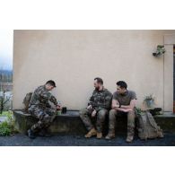 L'officier image Maxime prend une pause sur le perron d'une maison aux côtés du photographe Simon et de l'opérateur vidéo Julien pendant une marche entre le camp de Causse et la ville de Castres. b