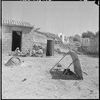 Centre de regroupement des environs de Mascara. Une famille devant leur maison.