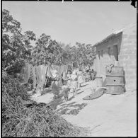 Centre de regroupement des environs de Mascara. Femme et enfants s'occupant du linge.