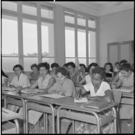 Jeunes femmes destinées à devenir monitrices assises à des bureaux dans une salle de classe.