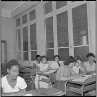 Jeunes femmes destinées à devenir monitrices assises à des bureaux dans une salle de classe.