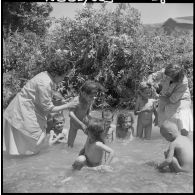 Les éducatrices des équipes médico-sociales itinérantes (EMSI) lavent les cheveux des enfants pendant qu'ils se baignent dans l'oued.